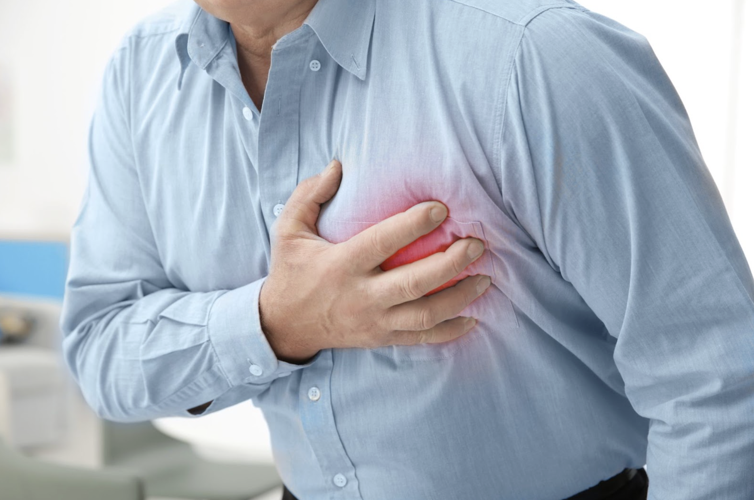 A person clutching their chest in discomfort, with a visual overlay of red indicating pain from a possible heart attack.